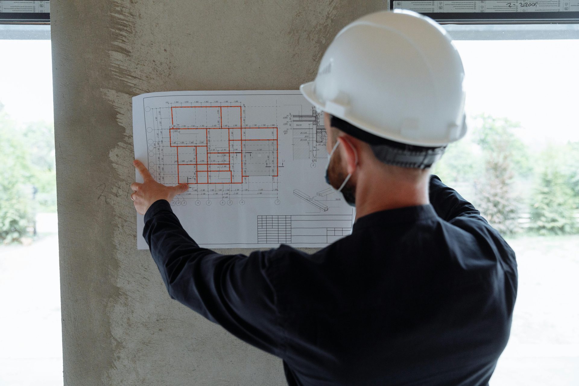Un ingénieur portant un casque de chantier examine les plans architecturaux sur un chantier de construction.