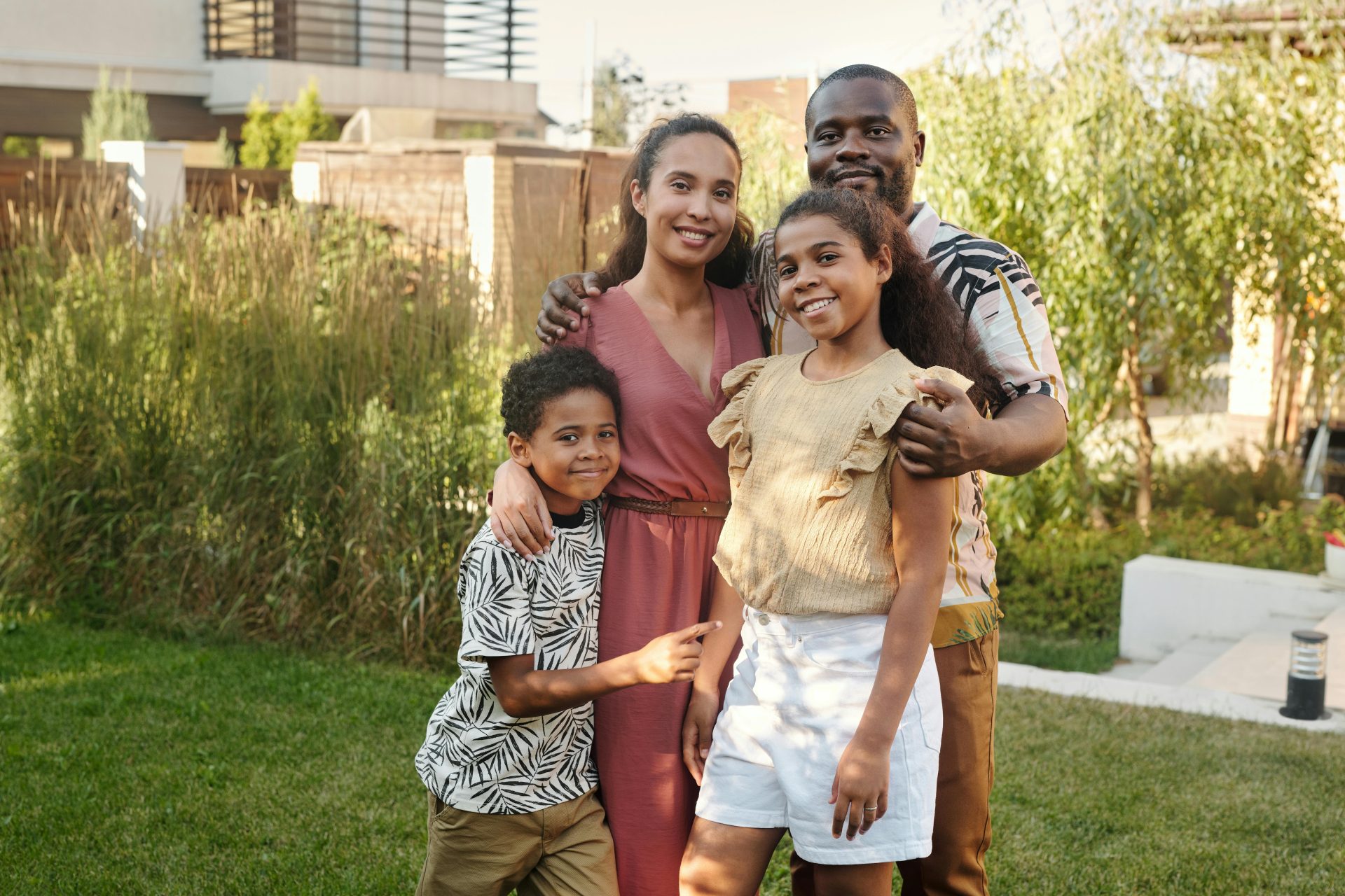 A joyful multicultural family smiling together in a sunlit garden setting.